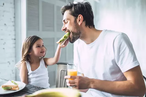 Holčička krmí tatínka sandwichem
