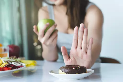 Žena odmítá donut a jí jablko