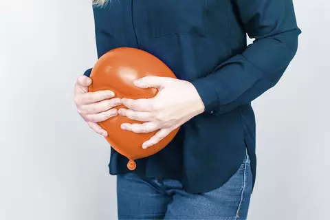 Žena drží nafouknutý balónek na břiše