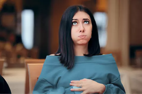 Žena se drží za plné břicho a odfukuje